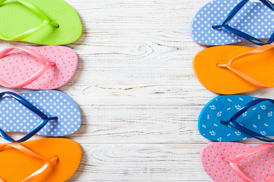 a lot of flip flop colored sandals, summer vacation on wooden background, copy space top view