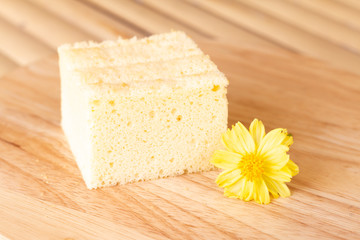Homemade sponge cake on wooden plate decorate with cute yellow flower in coffee's shop