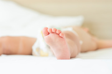 Fototapeta na wymiar Leg of a sleeping child in bed with white sheets. Concept of a good and sound baby sleep