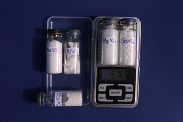 The process of weighing the reagents of salts of magnesium nitrate and calcium nitrate in two glass...