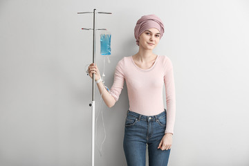 Young woman undergoing chemical therapy course against light background