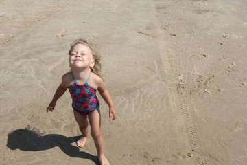 Fototapeta premium Happy little girl holding her face up to sun and sky
