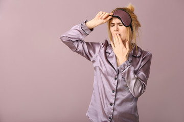 Sleepy woman with mask on color background