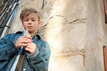 Homeless little boy eating bread outdoors