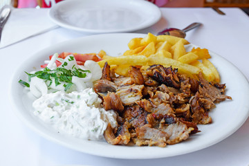 Greek Gyros with fries and vegetables and tzatziki sauce, Traditional turkish, greek meat food.
