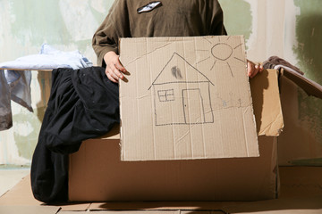 Homeless little boy with picture of house indoors