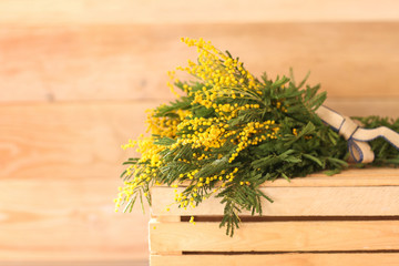 Bouquet of mimosa flowers on wooden box