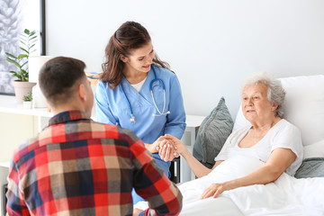 Senior woman with her grandson and caregiver in nursing home