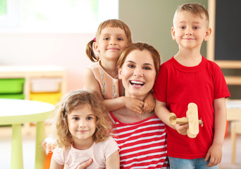 Nursery teacher with cute little children in kindergarten
