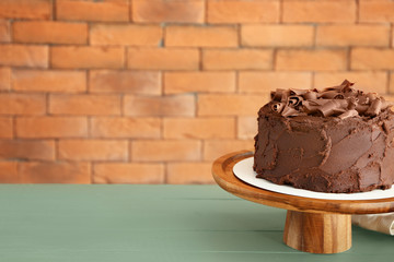 Stand with tasty chocolate cake on table