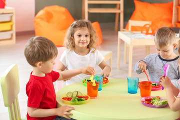 Cute little children eating tasty lunch in kindergarten