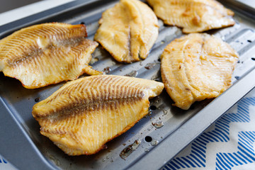 Close-up of tilapia fillets on a broiling pan. Recipe for healthy home dinner or lunch.