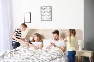 Obraz na płótnie Canvas Children scolding parent with addiction to modern technologies in bedroom
