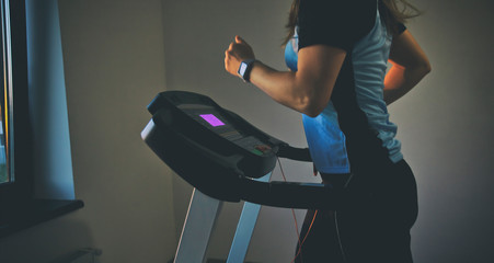The young woman does workout time on her treadmill in home
