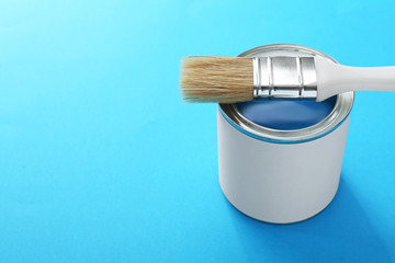 Can of paint and brush on color background