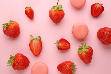 Sweet ripe strawberry and macarons on color background