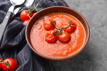 Bowl of tasty tomato cream soup on grey background