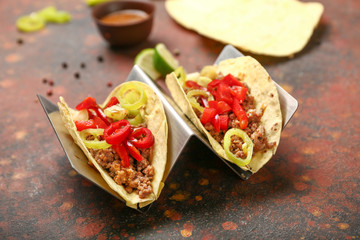 Stand with tasty fresh tacos on grunge background