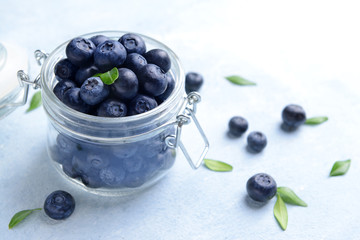 Jar with ripe blueberry on light background
