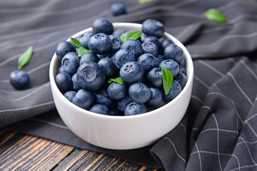 Bowl with ripe blueberry on wooden background