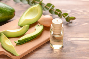 Fresh ripe avocados with essential oil on wooden table