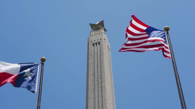 Texas Flag and American Flag Waving in Foreground of San Jacinto Monument in Houston, Texas