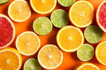 Many different citrus fruits on color background