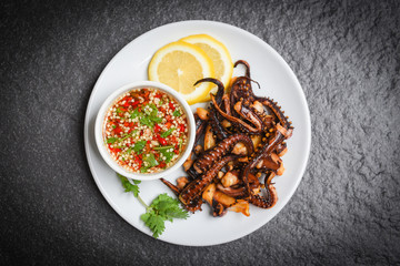 Octopus salad with lemon herbs and spices on white plate / Tentacles squid grilled appetizer food hot and spicy chilli sauce seafood cooked