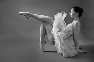 A young ballerina shows poses on the floor of the studio