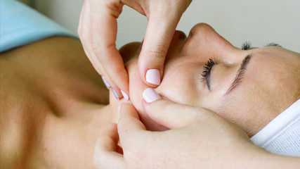 Young woman on healthy massage treatment in cosmetology spa center. Massage therapist is doing...