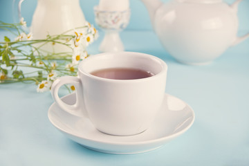 Morning. Breakfast. Cup of tea with milk, jar with milk, egg on the blue background