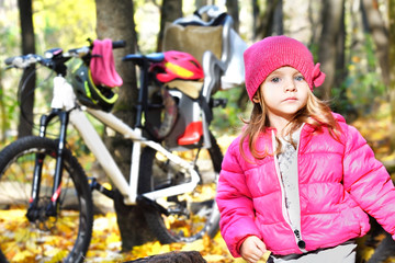Fototapeta na wymiar Portrait of a cute girl in the autumn forest on the background of a bicycle
