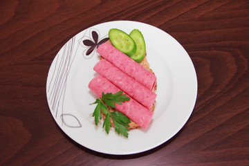 sandwich of rye bread with meat sausage, cucumbers and parsley