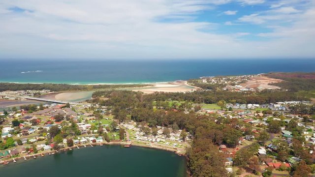 Aerial, tracking, drone shot, of beaches, the village and nature, on the coast of Burrill lake, on a sunny day, in New South Wales, Australia
