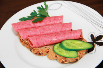 sandwich of rye bread with meat sausage, cucumbers and parsley