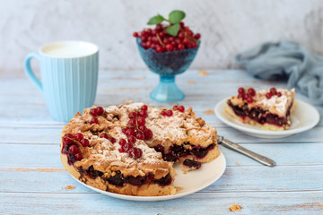 Tasty homemade cherry pie, cup of milk and fresh red currants in bowl on light blue background