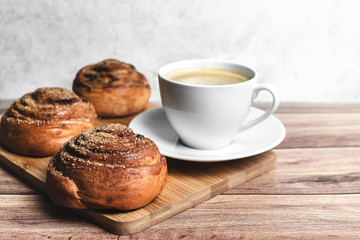 Perfect breakfast of two homemade cinnamon buns and coffee on wooden table. Rustic style. Close-up.