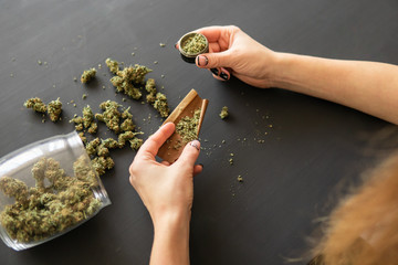 Woman preparing and rolling marijuana cannabis joint. Close up Woman rolling a marijuana joint. Pot...