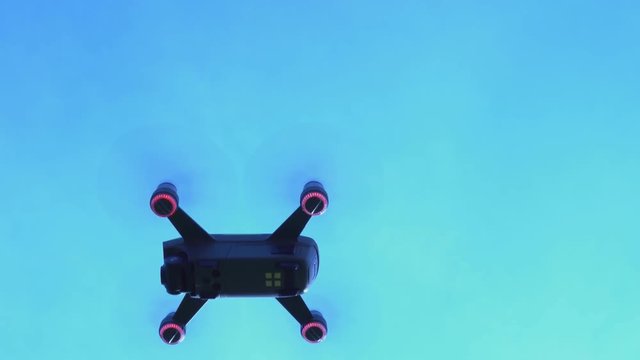 Drone flies in the air at low altitude against a blue sky and fly up fast. Modern new technology. Footage of the aircraft from below, unusual view.  Flying quadcopter above. Hobby. 4k.