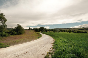 Fototapeta na wymiar View of rural landscape in spring, white country road and dramatic sky