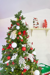 christmas tree decorated with balls and bows near white wall. Christmas room interior.