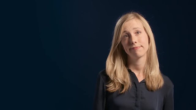 Portrait of an indifferent undecided blond woman  shrugging her shoulders making a clueless face