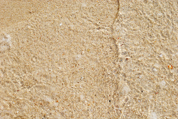 Sea water waves with bubbles on sand beach