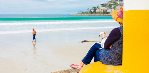 Woman at a beach with a dog on her lap