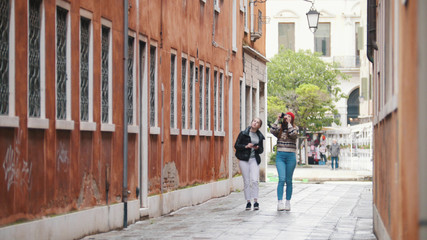 Fototapeta na wymiar Two young women travelers walking on the narrow streets of Venice, Italy