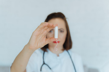 gynecologist with swab in his hand. Woman doctor shows tampon.