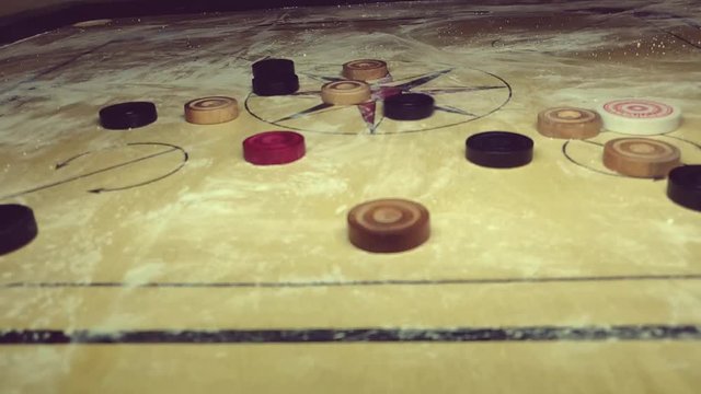 carom board coins hit by striker. all coins moving along with striker