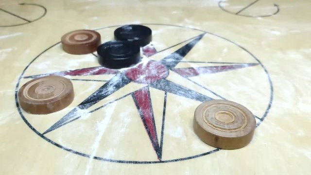 carom board coins hit by striker. all coins moving along with striker