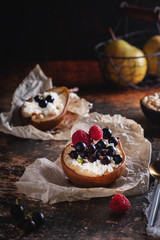 Baked pear with honey, cottage cheese, raspberries and currants. Fresh homemade dessert. Food composition in a low key. Close-up, copy space.