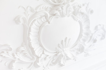 Luxury interior. Stucco elements on light wall. White patterned. Mouldings element from gypsum....
